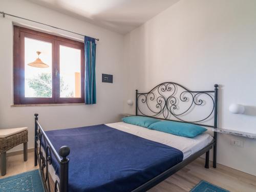 sypialnia z łóżkiem z niebieską pościelą i oknem w obiekcie Fronte Mare Costa Rei w mieście Costa Rei