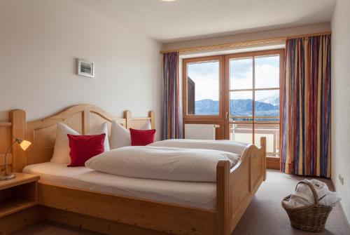 ein Schlafzimmer mit einem Bett mit roten Kissen und einem Fenster in der Unterkunft Hartungs Hoteldorf in Füssen
