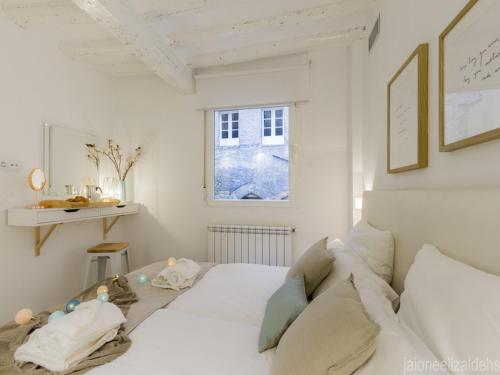 a white bedroom with a bed and a window at Center Pamplona Apartment in Pamplona