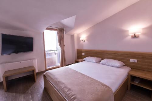 a bedroom with a large bed and a television at Hotel Lirak in Tetovo