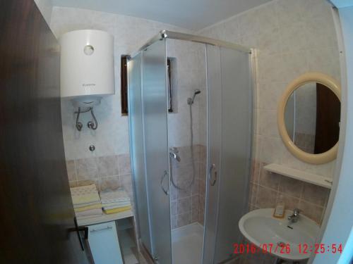 a bathroom with a shower and a sink and a mirror at Apartman Luburić in Pinezici