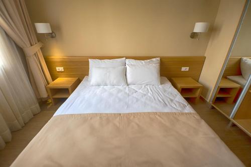a bed with white sheets and pillows in a room at Hotel Lirak in Tetovo