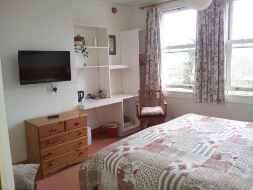 a bedroom with a bed and a tv on a wall at Acorn Guest House in Oxford