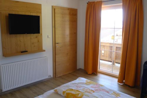 1 dormitorio con TV y puerta a un balcón en Ferienwohnung Zirmheim, en Westendorf