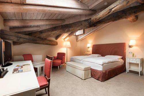 a bedroom with two beds and a desk and chairs at Grand Hotel Della Posta in Sondrio