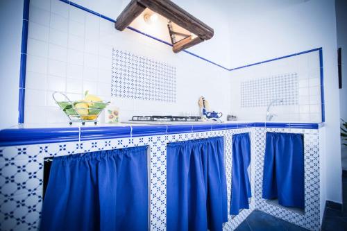 a kitchen with blue curtains and a sink at Appartamento La Marina in Castellammare del Golfo