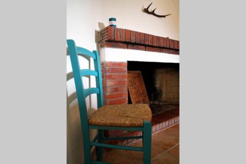 a blue chair sitting next to a brick fireplace at Casa del Cervo in Ingurtosu