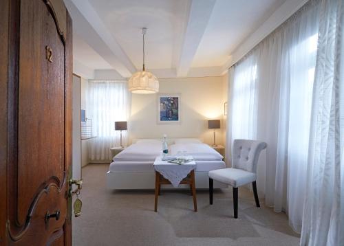 a bedroom with a bed and a table and a chair at Hotel Gasthof Zu den Linden in Oberhundem