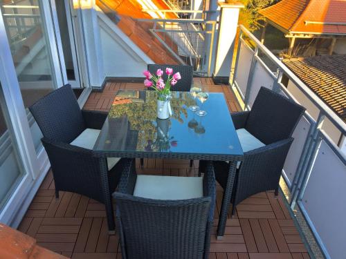 einen Tisch mit Stühlen und eine Vase mit Blumen auf dem Balkon in der Unterkunft Seestraße in Uhldingen-Mühlhofen