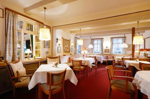 a restaurant with tables and chairs with white tablecloths at Hotel Gasthof Zu den Linden in Oberhundem