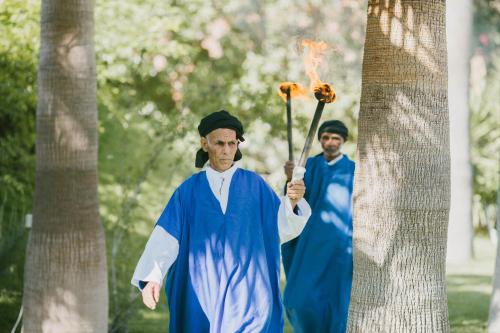 two men in robes standing next to a tree at Lodge K in Marrakech