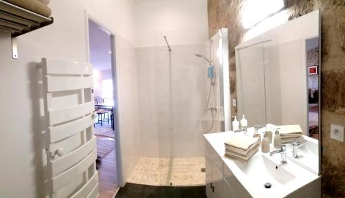 y baño blanco con lavabo y ducha. en Aumes Sweet Home Chambre d'Hôtes, en Aumes