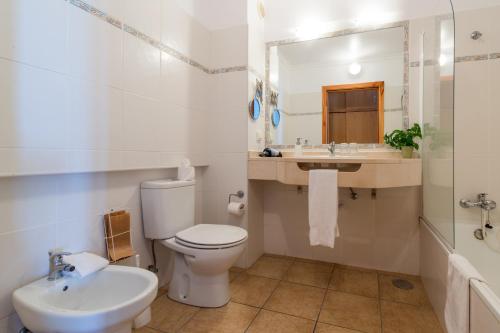 a white bathroom with a toilet and a sink at Quinta Alegre in Calheta