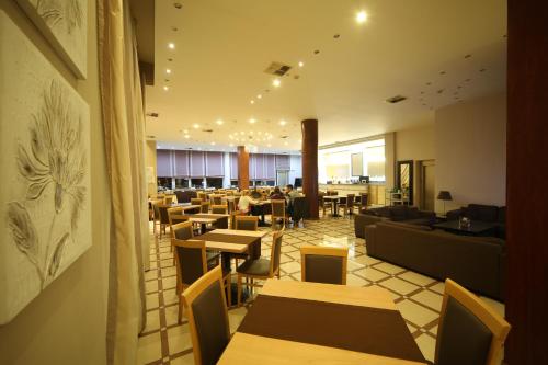 a restaurant with tables and couches and a cafeteria at Athina Airport Hotel in Thérmi
