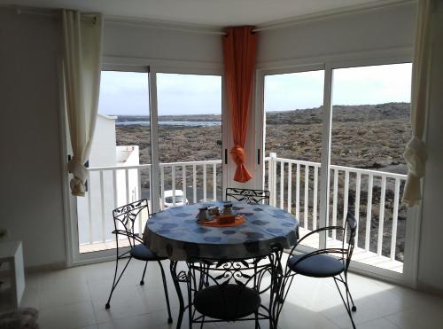 una mesa y sillas en una habitación con balcón en Orzola Para Descansar, en Orzola