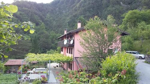 a pink house with a lot of plants in front of it at Rosa Dei Venti in Moggio Udinese