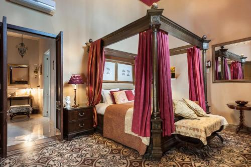a bedroom with a canopy bed with red curtains at Palazzo Muro Leccese Relais de Charme & Wellness in Muro Leccese