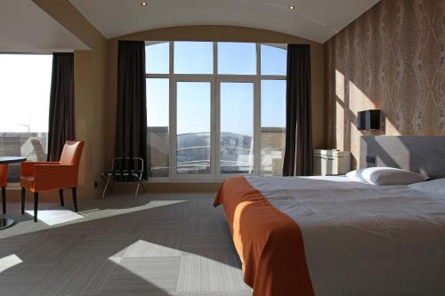 Schlafzimmer mit einem Bett, einem Schreibtisch und Fenstern in der Unterkunft Hotel Donny in De Panne