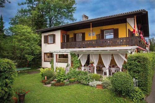 a house with a balcony with a table and chairs at Pension Stissen Haus am See in Faak am See