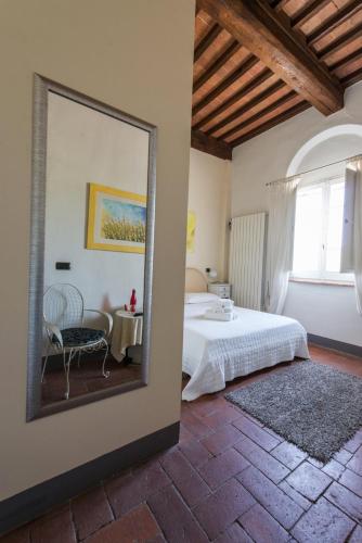 a mirror in a bedroom with a bed and a chair at L'Albero Di Gamelì in Chiusi