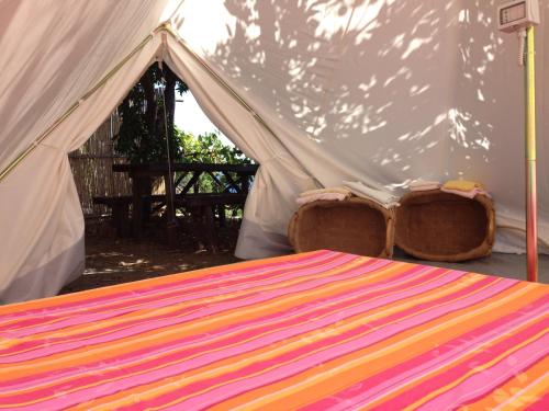 a bed in a tent with a colorful blanket at Bella Baia Campsite in Maiori
