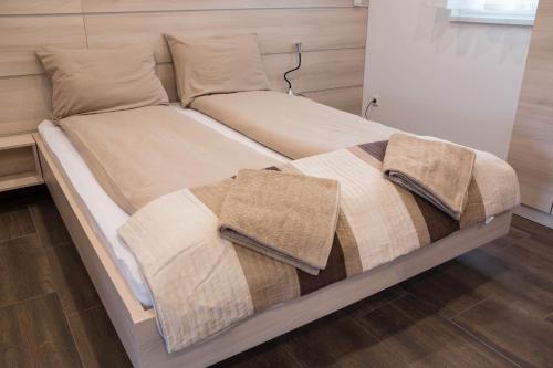 a bed with two blankets and pillows on it at Relax Apartmanház in Mórahalom