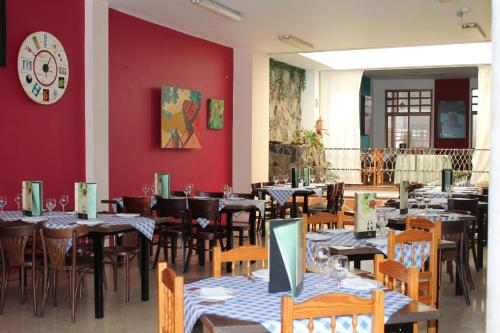 テロルにあるHotel el Pinoのテーブルと椅子、壁掛け時計のあるレストラン