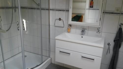 a white bathroom with a sink and a shower at Ferienwohnung am Zeitenweg in Windeck