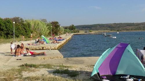 a group of people sitting on the beach near the water at Apartments CAPE Deluxe in Rtina