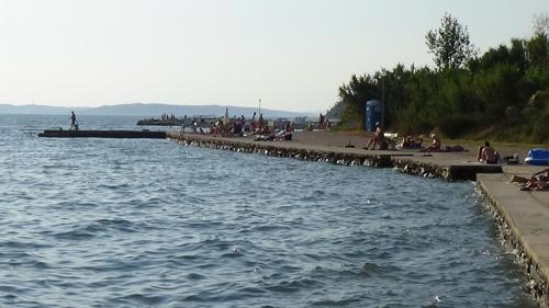 a group of people sitting on a beach next to the water at Apartments CAPE Deluxe in Rtina