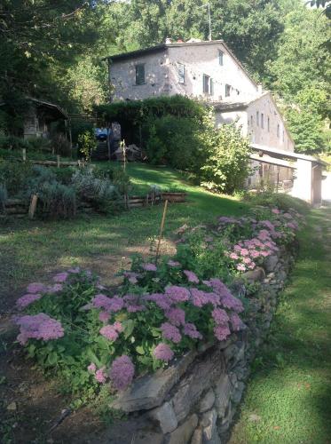 a stone wall with flowers in front of a house at Mulino Della Ricavata in Urbania