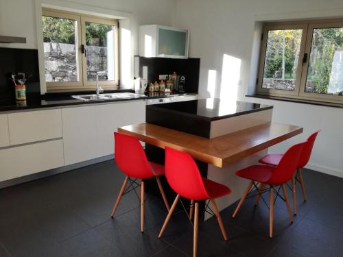 a kitchen with a wooden table and red chairs at Charme da montanha in Montaria