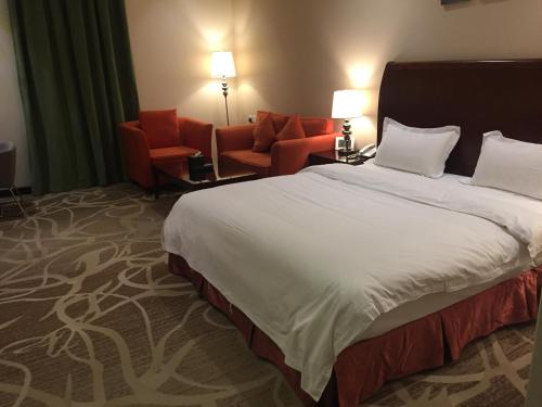 a hotel room with a large bed and two chairs at Asfar Plaza Hotel & Apartments in Riyadh