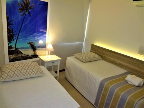 two beds in a room with a view of the beach at Open Door Apartamentos - Maceió - Alagoas - BRA in Maceió