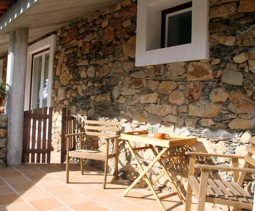 a wooden table and chairs on a stone wall at Couto dos Pardinhos in Monforte da Beira