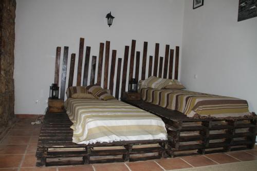 three beds are lined up against a wall at Couto dos Pardinhos in Monforte da Beira