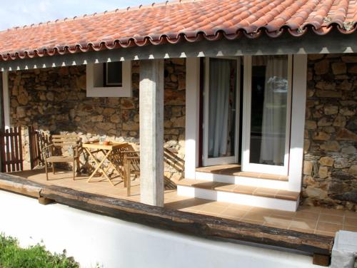 a house with a deck with a table at Couto dos Pardinhos in Monforte da Beira