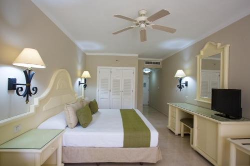 1 dormitorio con 1 cama y escritorio con TV en Bahia Principe Grand La Romana - All Inclusive, en La Romana