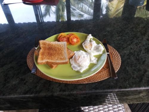 een bord met eten met eieren, toast en tomaten bij Villa Gede Private Guest House in Selemadeg