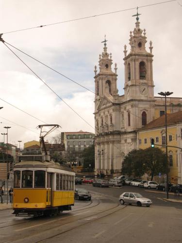 a yellow tram driving down a street in front of a church at Apartment Estrela Heart in Lisbon