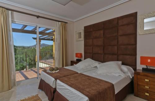 um quarto com uma cama grande e uma varanda em Montemares Golf Luxury Villas & Apartments at La Manga Club em La Manga del Mar Menor