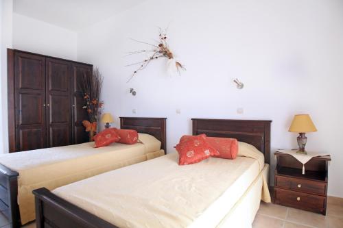 a bedroom with two beds with red pillows at Kos Island Studios in Kefalos