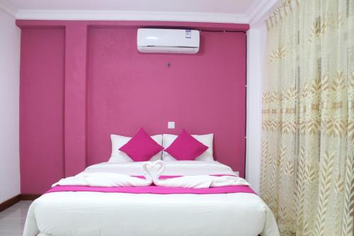 Un dormitorio con una pared púrpura y una cama en Believe Inn, en Nuwara Eliya