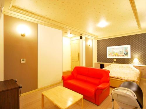 Zimmer mit einem roten Stuhl und einem Bett in der Unterkunft Hotel.COM (Adult Only) in Nagoya