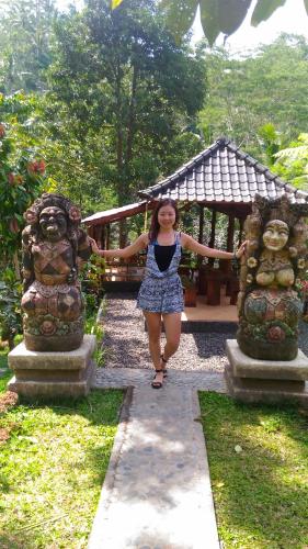 a woman standing between two statues in a garden at Bali Jungle Resort in Tegalalang