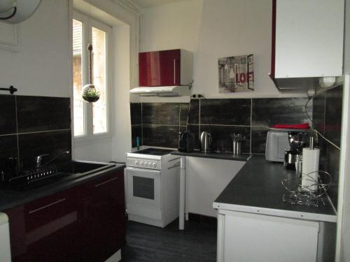 a kitchen with white appliances and a black counter top at Les Croisiers in Caen