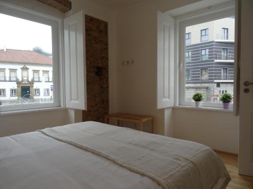 1 dormitorio con 1 cama y 2 ventanas en Alojamentos Casa Facha Menta en Portalegre