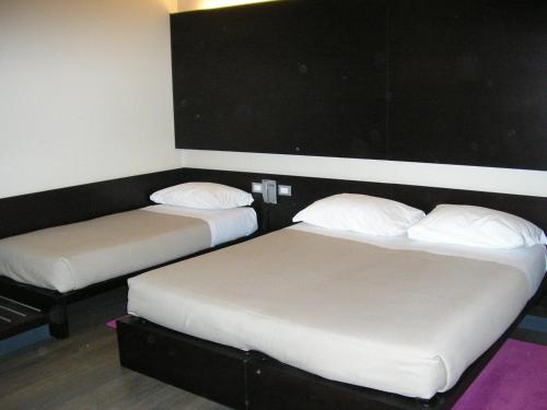 two beds in a room with white sheets and pillows at Art Hotel Udine in Udine