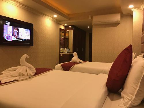 a hotel room with two beds and a flat screen tv at Hyders Park The Business Hotel in Thanjāvūr