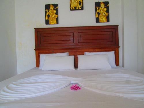 a bed with a white sheets and a pink flower on it at Kandyan Sweet Villa in Kandy